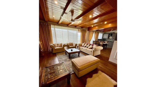 Un salon spacieux avec un plafond en bois, un ensemble de canapés, une table basse et un tapis en fourrure.