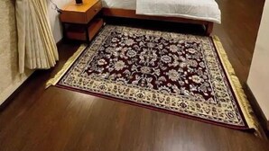 Une chambre d’hôtel avec un lit, des tables de chevet, un tapis à motifs et un ventilateur de plafond.