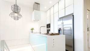 A modern kitchen with a stainless steel refrigerator, a built-in oven, and a glass island counter. - Genteel Home Atocha II (Madrid)