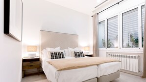 A bedroom with a large bed, two bedside tables, a window with curtains, and a radiator. - Genteel Home Atocha II (Madrid)