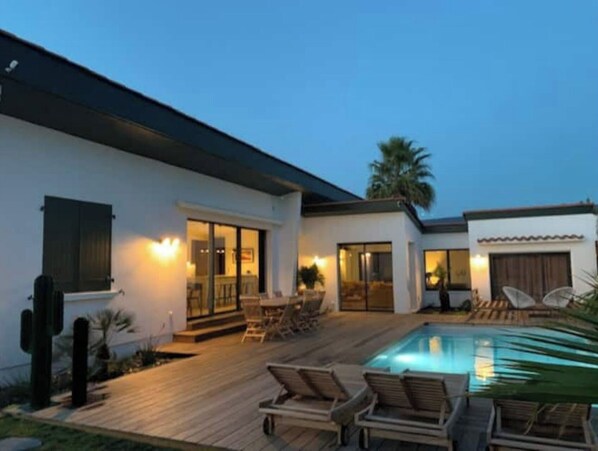 Relax in a spacious outdoor area with a pool, lounge chairs, and a covered seating area.