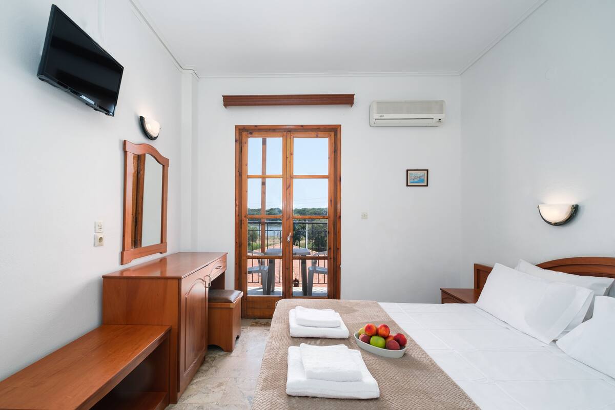 Ein Schlafzimmer mit Bett, Nachttischen, Fernseher, Spiegel und einem Fenster mit Blick.