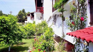 A row of white buildings with red roofs and balconies, surrounded by lush greenery and flowering plants. - Koukounaries Beach Hotel (Skiathos)