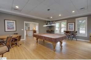 A spacious room with a pool table, wooden dining table, and chairs.