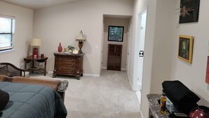 A living room with a sofa, a TV, a wooden cabinet, and a window with blinds.