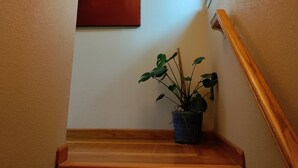 A staircase with a wooden handrail, a potted plant, and a red artwork on the wall.