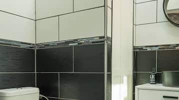 Un baño con inodoro, lavabo y zona de ducha.