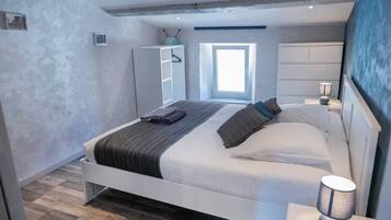 A modern bedroom with a bed, bedside table, and a window.