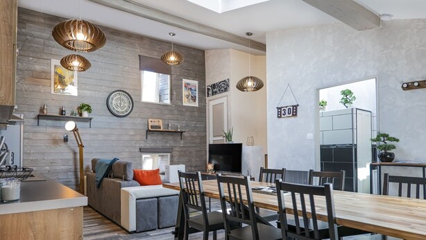 Una cocina moderna con comedor, suelo de madera e iluminación colgante.