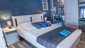 Un dormitorio moderno con una cama grande, mesitas de noche y vistas al comedor.