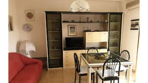 Un espace de vie compact comprenant un coin repas, un canapé et un téléviseur.