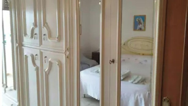 Une chambre à coucher avec un lit, une armoire et un tableau accroché au mur.