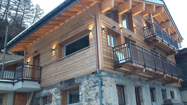 A multi-story wooden cabin with balconies and large windows.