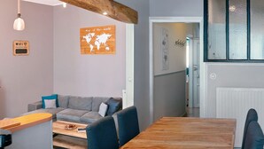 Ein zeitgemäßer Wohnraum mit grauem Sofa, Esstisch aus Holz und einer Weltkarte an der Wand.