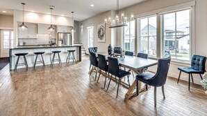 Une cuisine moderne dotée d’un îlot central, de tabourets de bar et d’un coin repas avec une grande table et des chaises.