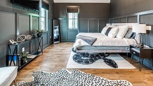 Une chambre moderne avec un grand lit, une console, un téléviseur et une fenêtre donnant sur un beau paysage.