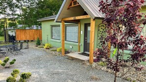 Un bâtiment d’un seul étage, à l’extérieur vert, doté d’un porche en bois et d’une allée gravillonnée.