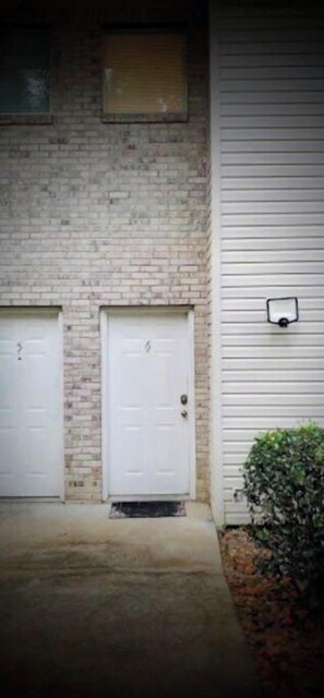 Stylish residential building with a brick facade and garage doors, featuring a small overhang and security camera.