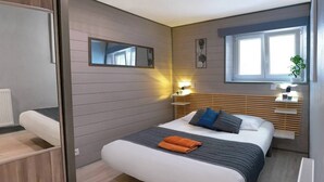 A modern bedroom with a bed, bedside tables, a mirror, and a window.