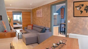 A modern living room with a grey sectional sofa, a wooden dining table with candles, and a world map on the wall.