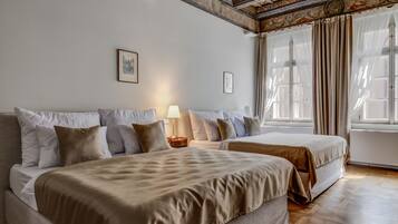 A hotel room with two beds, a nightstand, a lamp, and a large window with curtains.
