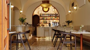 A restaurant interior with a bar area, seating, and a wine display. - Hotel Nerudova 211 (Prague)