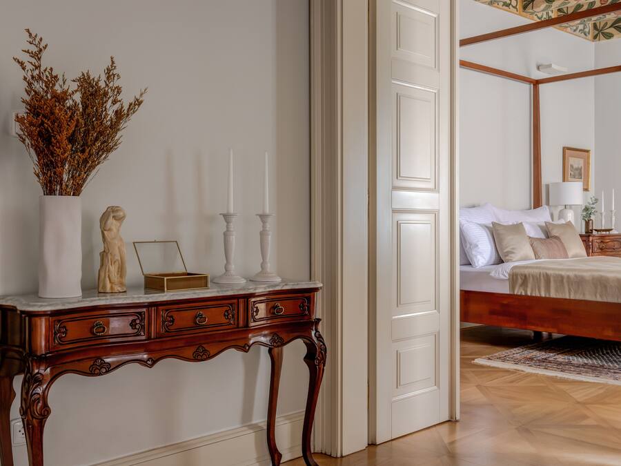 Une chambre avec un lit en bois, des murs blancs et un plancher en bois.