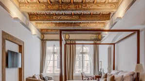 A four-poster bed with a wooden frame, a sofa, and a television mounted on the wall. - Hotel Nerudova 211 (Prague)
