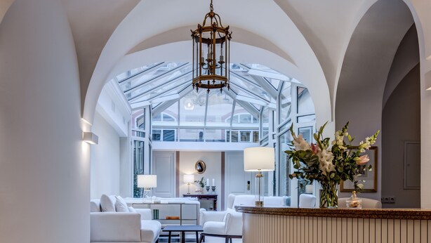 A spacious interior with a high ceiling, a central seating area, and a reception desk. - Hotel Nerudova 211 (Prague)