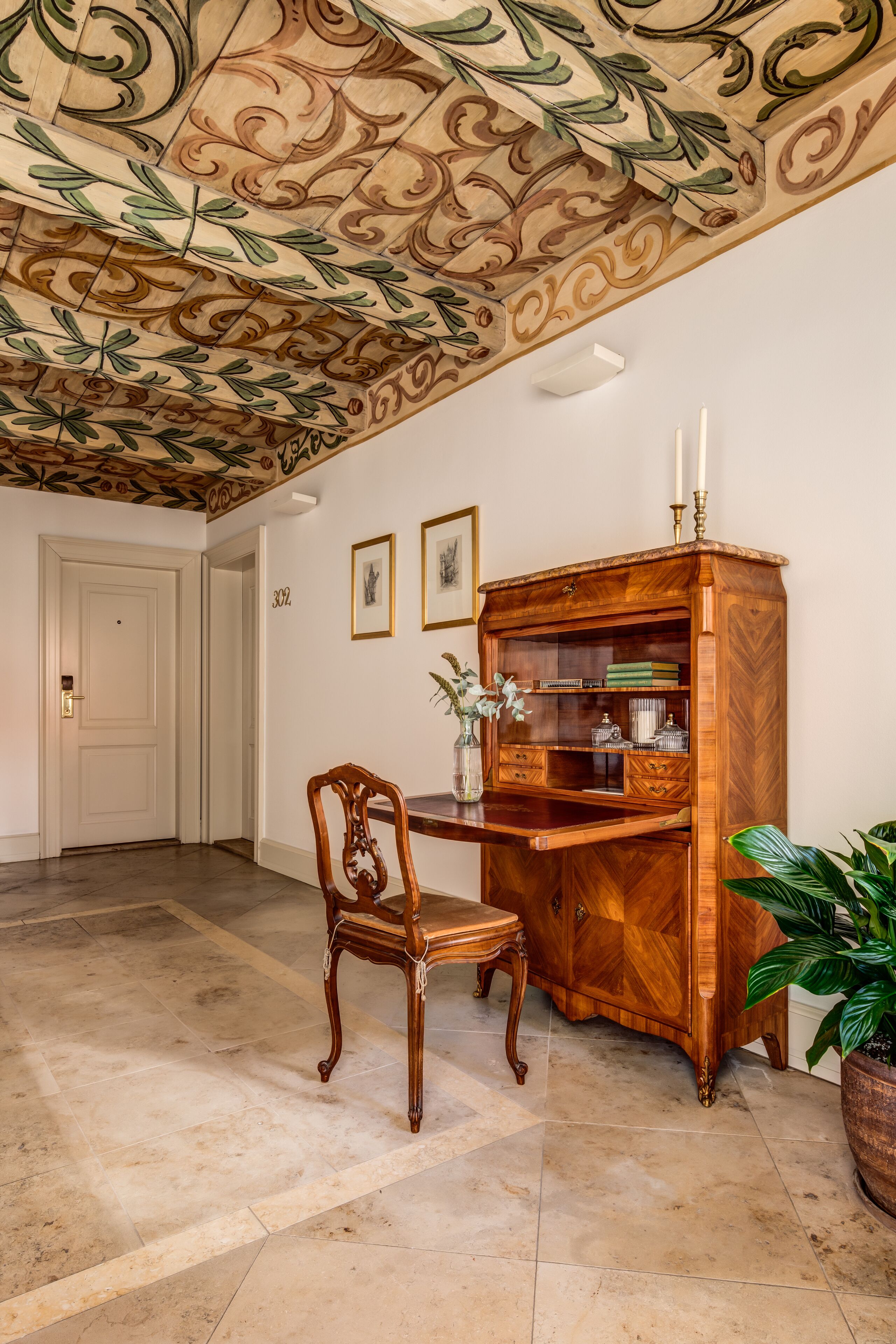 Una habitación con un armario de madera, una silla y una planta en maceta.