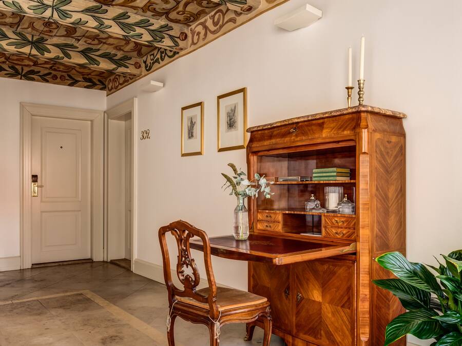 Una habitación con un armario de madera, una silla y una planta en maceta.