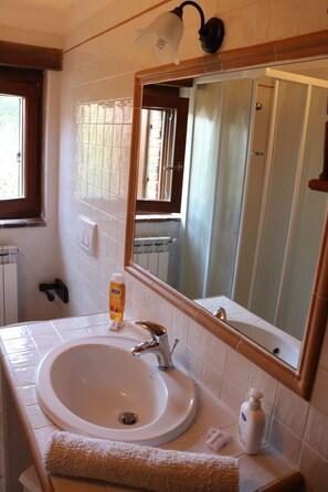 Une salle de bain avec un lavabo blanc, un miroir et une fenêtre.
