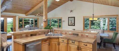 Una cocina amplia con armarios de madera, lavavajillas integrado y grandes ventanas con vistas al exterior.