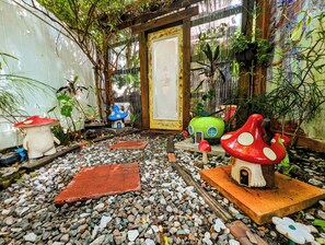 Ein Gartenweg mit pilzförmigen Pflanzgefäßen und einer rustikalen Holztür.