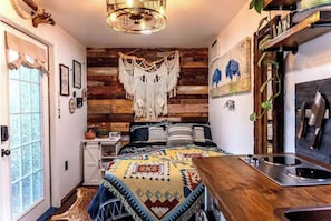 Cozy bedroom with a bed, wooden nightstand, and bench with sink.