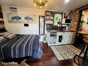 Ein kleines Zimmer mit Bett, Küchenzeile und Essecke.