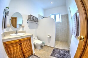 A modern bathroom with a sink, mirror, toilet, and shower.
