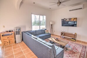 A living room with a sofa, a coffee table, a TV, and a ceiling fan. - 1BR w Private Sunset Rooftop - Palmas 3A (Bucerías)