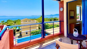 Un balcone con vista sul mare, una piscina e un tavolo con una lanterna.
