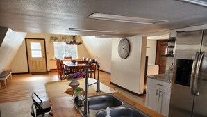 Een keuken met een dubbele spoelbak, een koelkast en een eethoek met houten stoelen en een tafel.