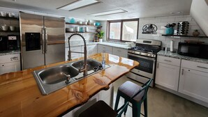 Een moderne keuken met een roestvrijstalen koelkast, een ingebouwde waterdispenser, een houten kookeiland met een spoelbak en een gasfornuis.