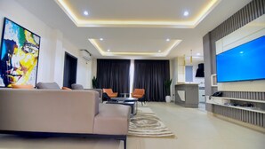 Una sala de estar moderna con un sofá, sillas, un televisor y un cuadro.