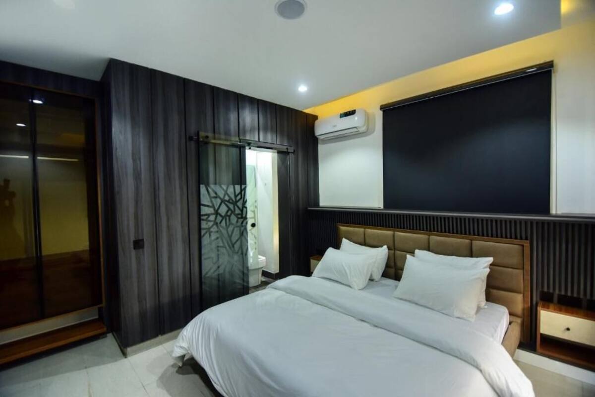 A modern bedroom with a large bed, a wardrobe, and an air conditioning unit.