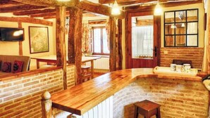 Een rustiek interieur met zichtbare houten balken, een houten bar en een bakstenen muur.
