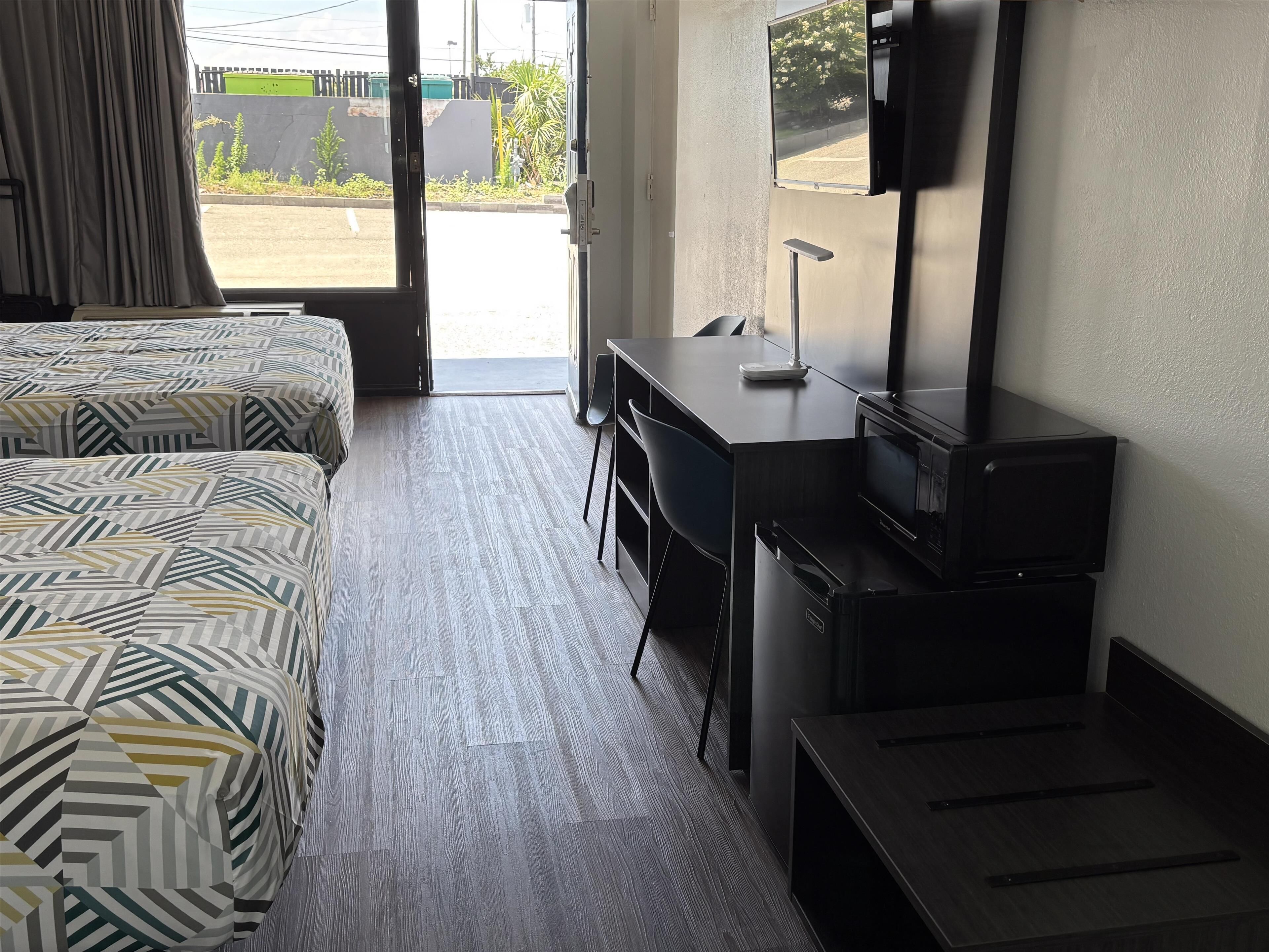 A hotel room with two beds, a desk, a chair, a TV, and a microwave.