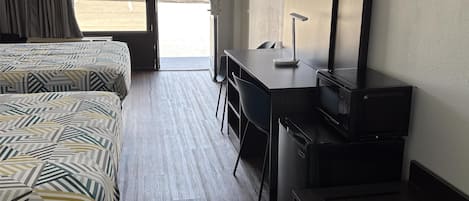 Een hotelkamer met twee bedden, een bureau, een stoel, een televisie en een magnetron.