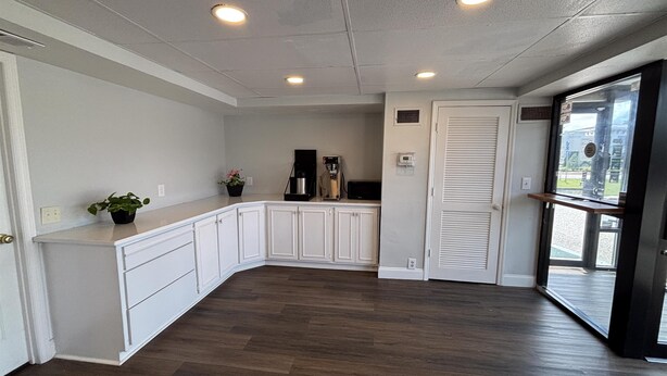 A modern kitchen with white cabinetry, a wooden floor, and recessed ceiling lights. - Motel 6 – Conway, SC (Conway)
