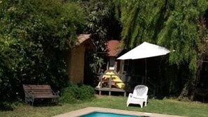 A rectangular swimming pool with clear blue water, surrounded by a concrete deck. There is a white umbrella and a white plastic chair near the pool. - hermosa casa con piscina olmue (Olmue)