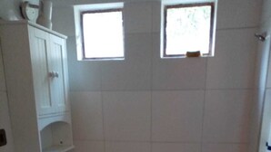 A small, clean bathroom with a toilet, sink, and two windows. - hermosa casa con piscina olmue (Olmue)