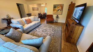 A living room with a sofa set, a coffee table, a rug, a TV, and a painting on the wall. - Cozy, Peaceful and Quiet Deerwood Cottage (Lake City)